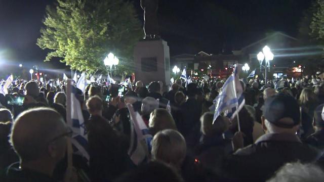 Hundreds of people stand outside the Rockland County Courthouse, many holding Israeli flags. 