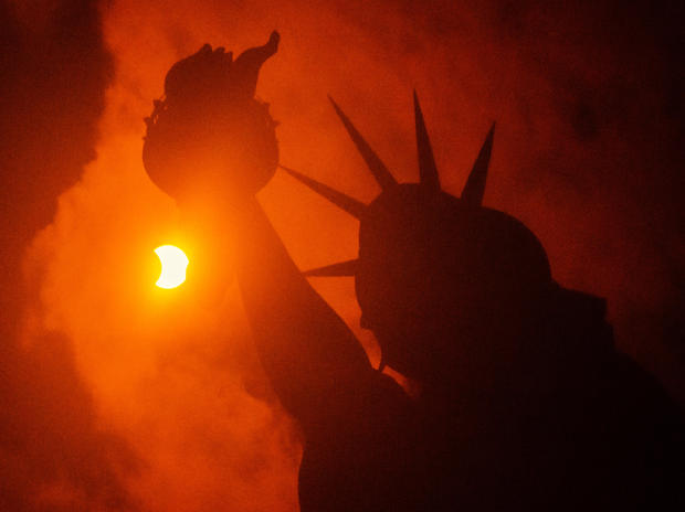 The solar eclipse is seen behind the Statue of Liberty at Liberty Island on August 21, 2017 in New York City. 