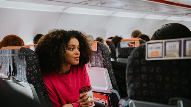 A young woman looks pensive on a plane 