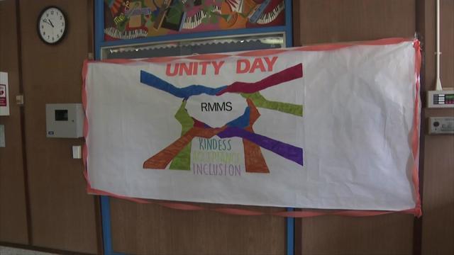 A banner with a drawing of colorful hands and arms forming a heart around the letters "RMMS." The top of the banner reads "Unity Day" and the bottom reads, "Kindness, acceptance, inclusion." 