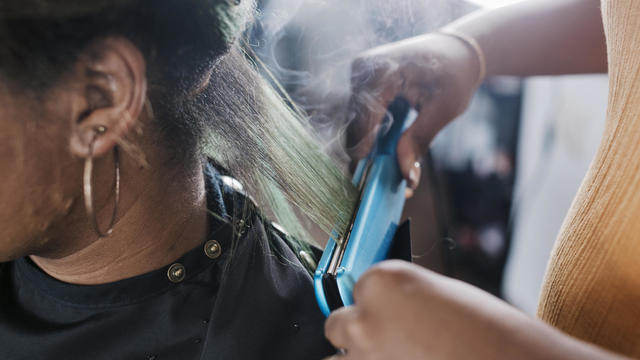 Close Up Of Black Hairdresser Straightening Client's Hair 