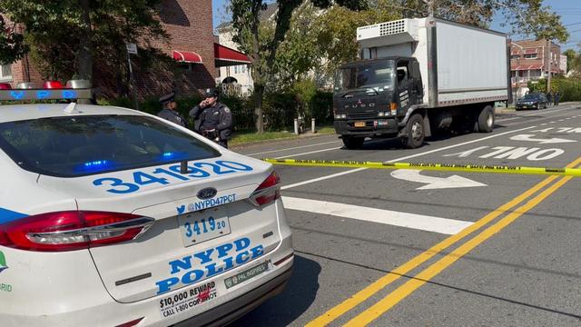 A box truck behind crime scene tape with an NYPD vehicle in the foreground. 