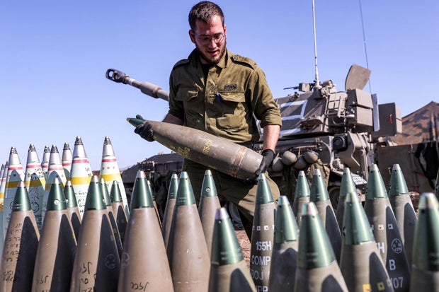 An Israeli army soldier carries a 155mm artillery shell near a self-propelled howitzer deployed at a position near the border with Lebanon in the upper Galilee region of northern Israel on Oct. 18, 2023.