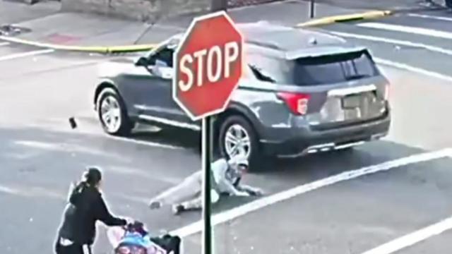 An SUV drives through an intersection as an 11-year-old boy lays on the pavement after being struck. 