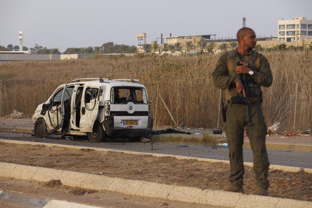 An Israeli soldier stands near a vehicle hit by a rocket fired by Hamas militants, in Netivot, Israel, on Sunday, Oct. 22, 2023