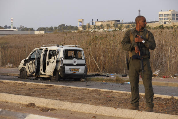 An Israeli soldier stands near a vehicle hit by a rocket fired by Hamas militants 