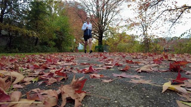Alice Yu runs along a leaf-covered path. 