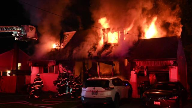 Flames engulf a two-story home at night. 