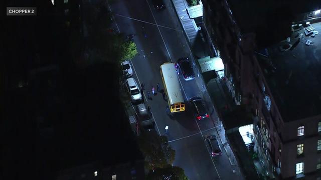 An aerial view of police officers looking at a street near a school bus. 