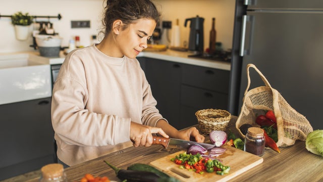 Woman cutting fresh organic vegetables for salad on kitchen. Sustainable lifestyle