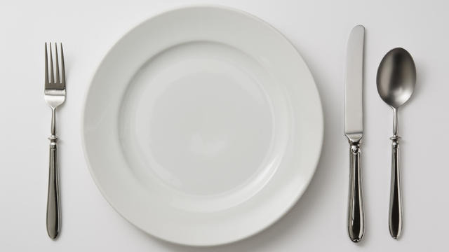 Isolated shot of plate with cutlery on white background 