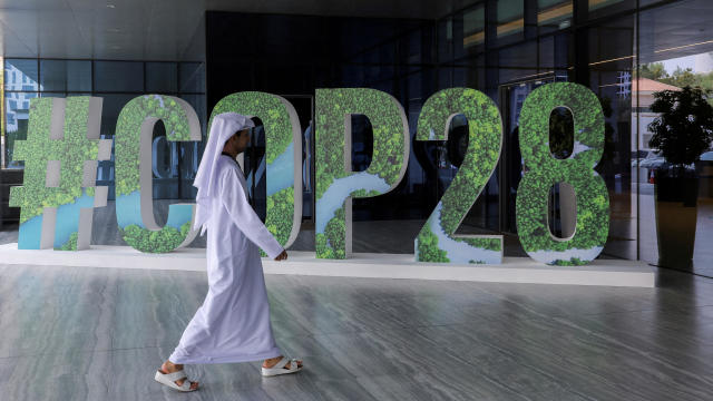 A person walks past a "#COP28" sign in Abu Dhabi 