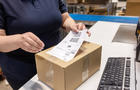 Close-up of woman worker sticking a label on a delivery box at warehouse 