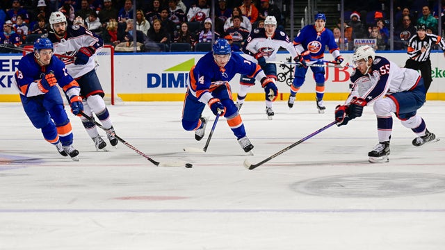 Mathew Barzal #13 and Bo Horvat #14 of the New York Islanders battles for the puck with David Jiricek #55 of the Columbus Blue Jackets during the first period at UBS Arena on December 07, 2023 in Elmont, New York.