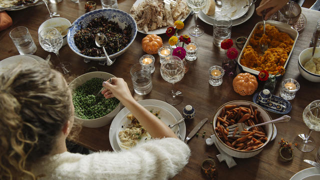 Teenage girl having food while sitting at dining table during Thanksgiving 