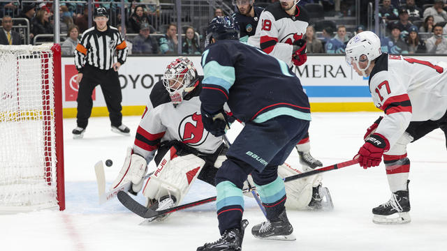 New Jersey Devils goaltender Akira Schmid (40) defends as Seattle Kraken right wing Jordan Eberle, foreground, misses a shot during the third period of an NHL hockey game Thursday, Dec. 7, 2023, in Seattle. 