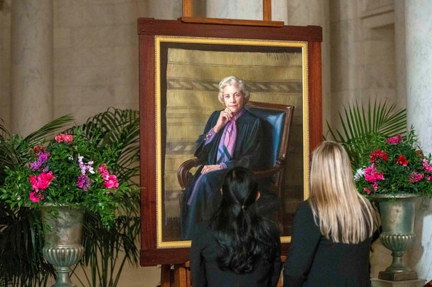 Mourners look at a portrait of retired Supreme Court Justice Sandra Day O'Connor, who lay in repose in the Great Hall at the Supreme Court in Washington, Monday, Dec. 18, 2023.