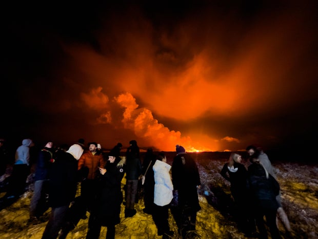 People gather to watch as a volcano erupts on the Reykjanes Peninsula, north of Grindavik, Iceland, on Dec.18, 2023