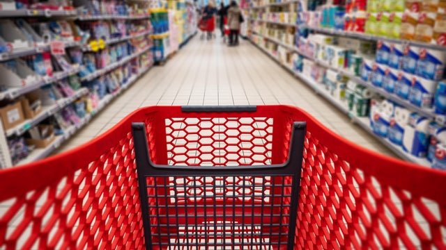 Personal perspective of a shopper pushing shopping trolley along product aisle while shopping in a supermarket. Super Market tinned and canned produce Aisle with Blurred shelves and products to make it generic.