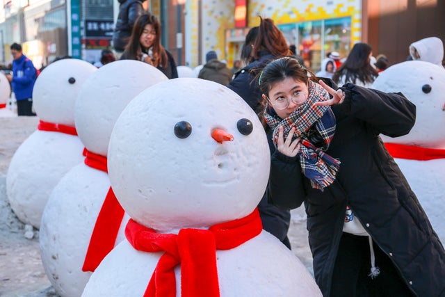 People pose for photos next to snowmen decorations in China 