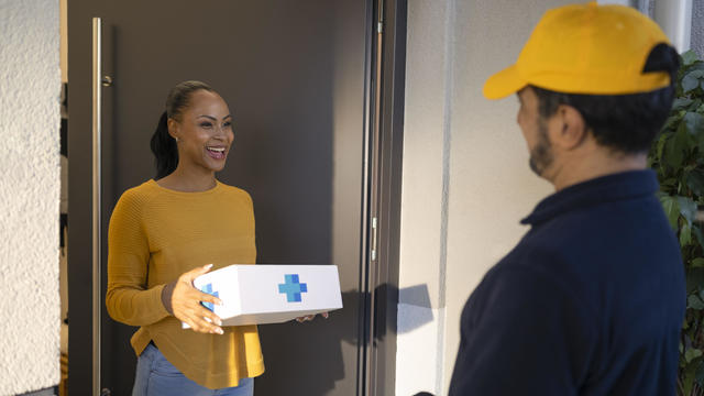 Delivery person delivering medicine to woman 