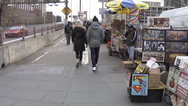 Vendors and food carts line the walkway heading towards the Brooklyn Bridge. 