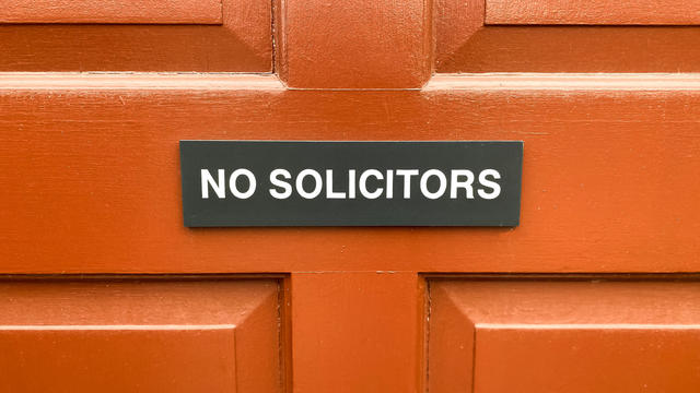 "no solicitors" sign on bright orange red door 