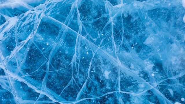 Surface of winter ice on Baikal lake in Siberia . Blue background of Ice texture 