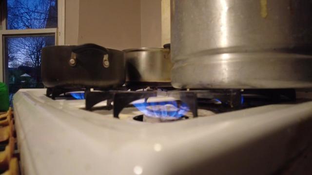 Pots of water on top of a stove with all of its burners on. 