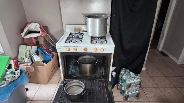 An open oven with pots of water inside. There is another pot of water on the stove and all four burners are on. 