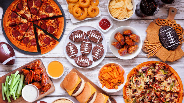 Super Bowl or football theme food table scene, above view on white wood 