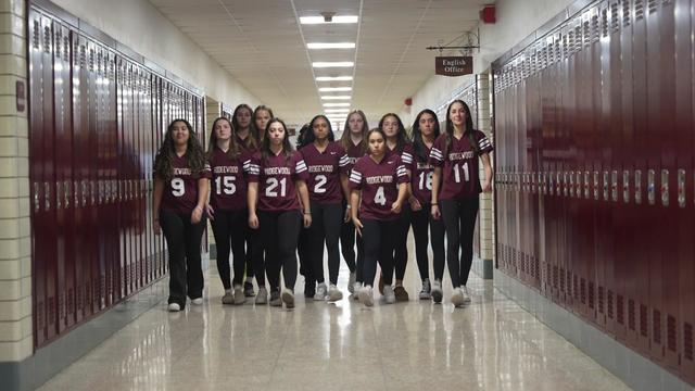 Members of the Ridgewood girls flag football team walk down a school hallway. 