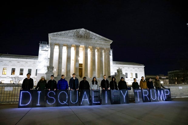 MoveOn members hold signs that read "Disqualify Trump" during a rally outside the Supreme Court on Feb. 1, 2024, in Washington, D.C.