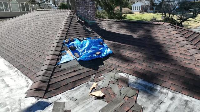 A blue tarp covers a hole in the roof of a home. 
