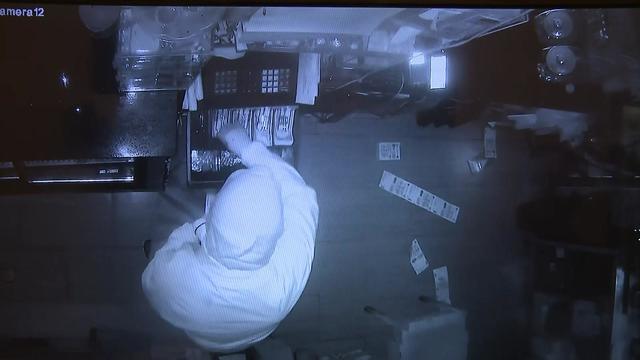 Surveillance footage shows an individual taking cash out of a bodega register. 