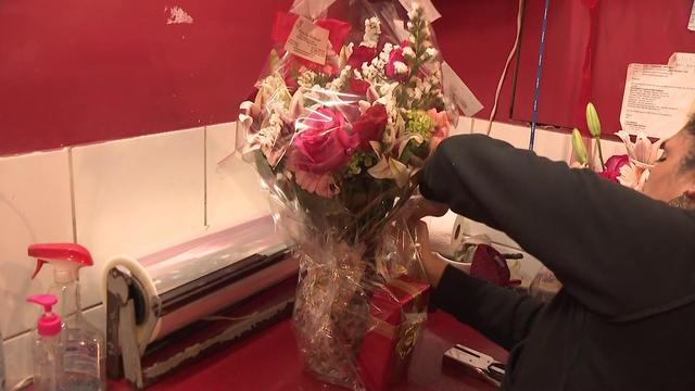 An employee arranges flower in a vase inside a store. 