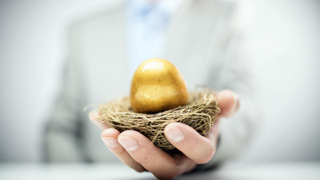 Retirement savings golden nest egg in businessman hand 