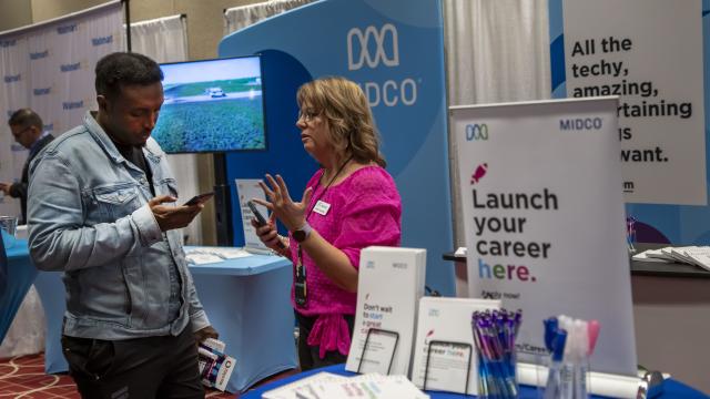 Minneapolis, Minnesota. People of color Career Fair. A networking and hiring event for professionals of color. A person checks out career opportunities at the Midco booth. 