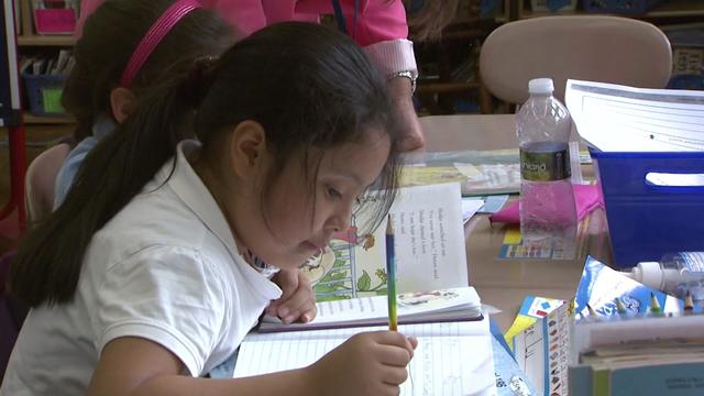 A New York City elementary school student writes in a notebook in a classroom. 