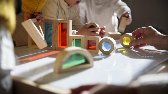 Little kids playing with colorful wooden building blocks on the table 