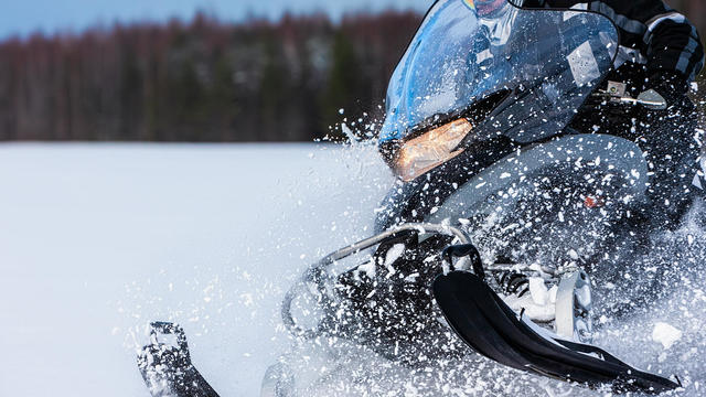 In deep powder snowdrift snowmobile rider driving fast. 
