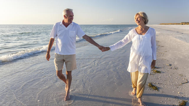 Smiling senior couple holding hands on a beach 