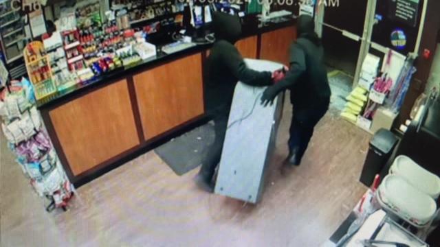 Surveillance video shows two individuals dragging an ATM out of a store. 