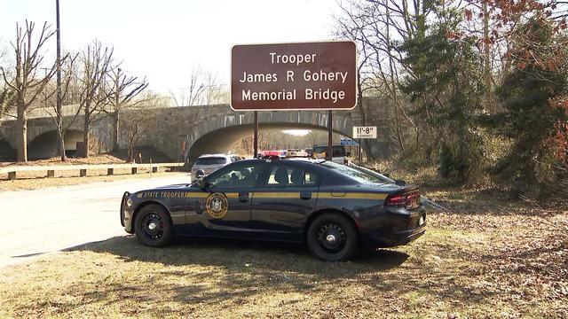 A New York State Police vehicle sits parked under a sign reading "Trooper James R. Gohery Memorial Bridge" on the Wantagh Parkway. 