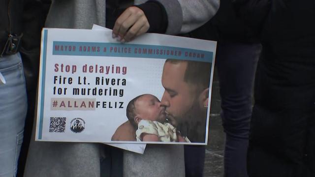 An individual holds a sign that reads "Stop delaying. Fire Lt. Rivera for murdering #AllanFeliz." The sign also has a photo of Felix kissing a baby. 
