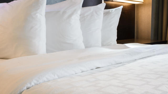 Neatly made hotel bed with 4 pillows 