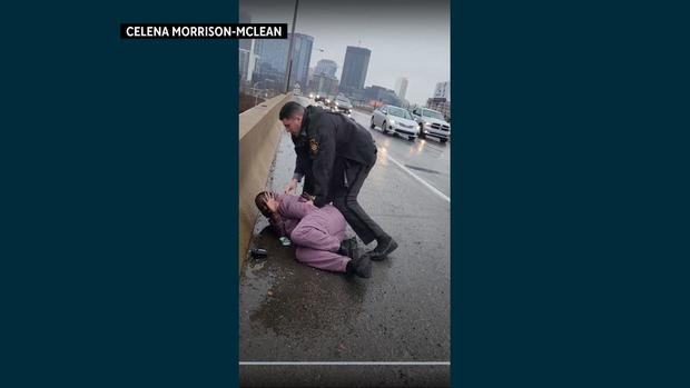 A screenshot from a social media video showing a person being arrested on a highway. 