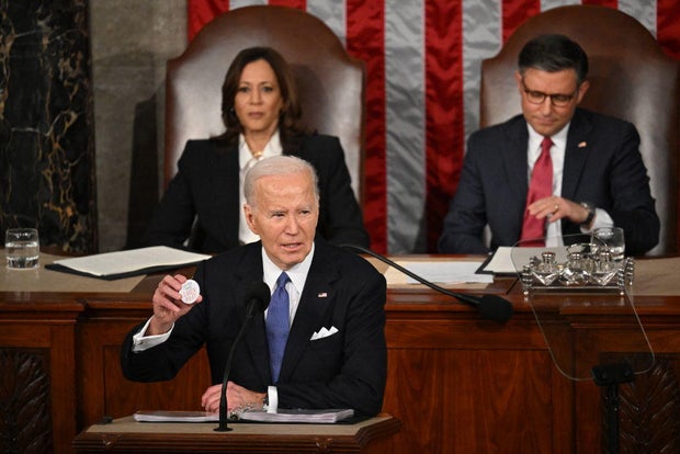 President Biden holds a button with Laken Riley's name on it while delivering the State of the Union address on March 7, 2024.