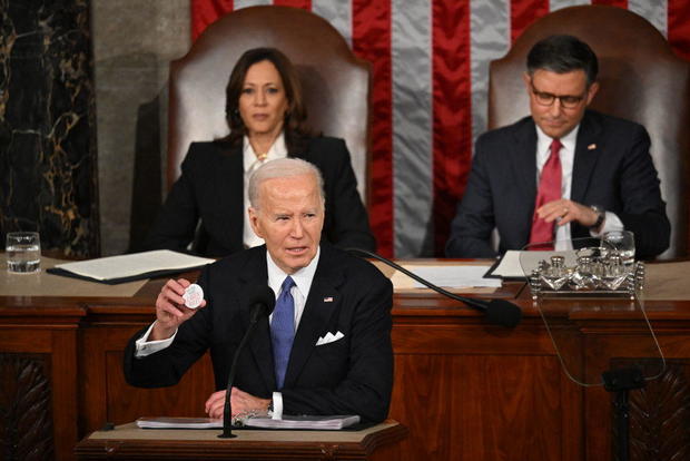 President Biden holds a button with Laken Riley's name on it while delivering the State of the Union address on March 7, 2024. 