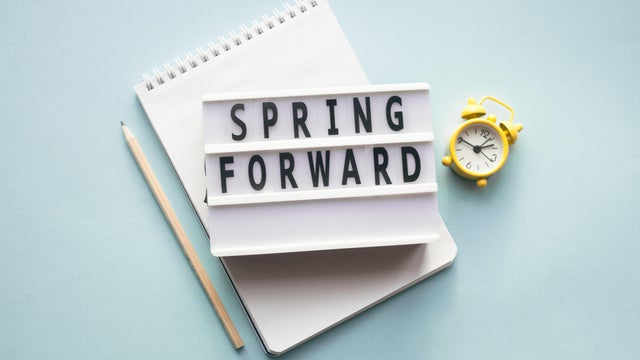 Spring forward concept. Alarm clock, pen and notepad. Daylight saving time. 